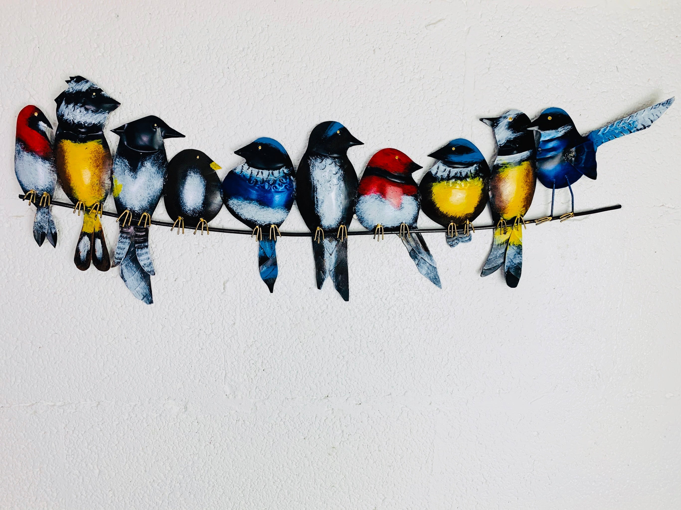 front view of metal birds on a wire hung on white wall
